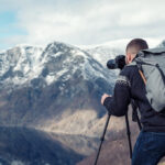 A person with a camera on a mountain Description automatically generated with low confidence